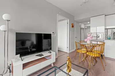 a living room with a table and a large tv at New Cozy 1 Bedroom & Den Condo in Downtown Toronto in Toronto