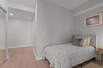 a bed in a room with white walls at New Cozy 1 Bedroom & Den Condo in Downtown Toronto in Toronto
