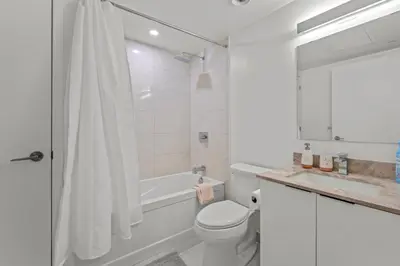 a white bathroom with a tub and a toilet and a sink at New Cozy 1 Bedroom & Den Condo in Downtown Toronto in Toronto