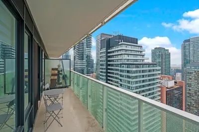 a balcony with a table and a view of a city at New Cozy 1 Bedroom & Den Condo in Downtown Toronto in Toronto