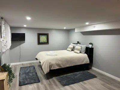 a bedroom with a bed and a flat screen tv at 1 Bedroom Basement with parking and Backyard in Hamilton