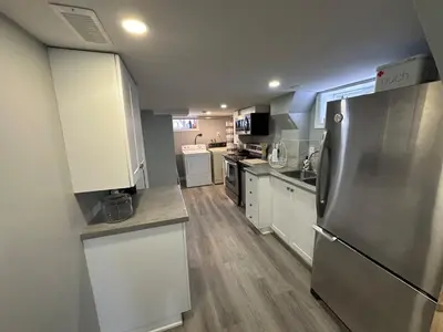 a kitchen with a stainless steel refrigerator and white cabinets at 1 Bedroom Basement with parking and Backyard in Hamilton