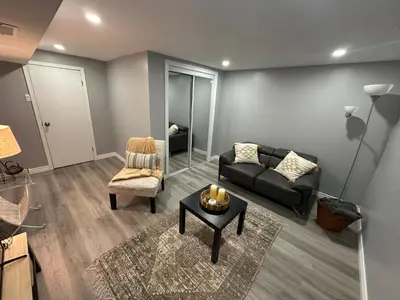 a living room with a black couch and a chair at 1 Bedroom Basement with parking and Backyard in Hamilton