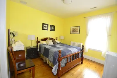 a bedroom with a bed and yellow walls and a window at Ambassador B&B Guest Home in Stratford