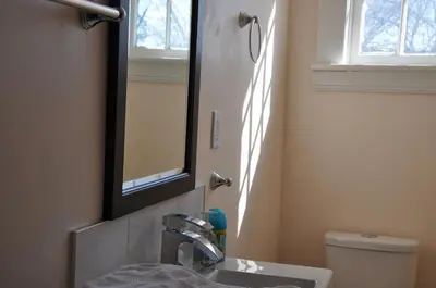a bathroom with a sink and a mirror and a toilet at Ambassador B&B Guest Home in Stratford