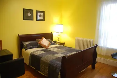 a bedroom with a bed and a lamp and yellow walls at Ambassador B&B Guest Home in Stratford
