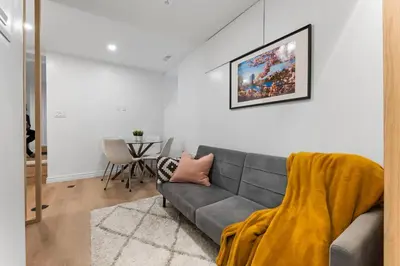 a living room with a gray couch with a yellow blanket at High Park Oasis Modern 1B1B, Kitchen, Laundry in Toronto