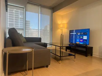 a living room with a couch and a tv at RivetStays - Dan Leckie Suite in Toronto