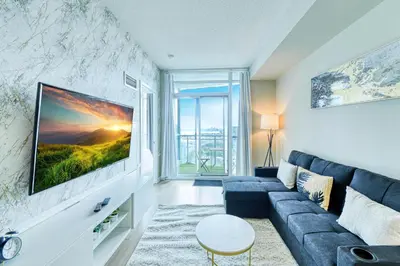 a living room with a blue couch and a tv at RivetStays - Dan Leckie Suite in Toronto