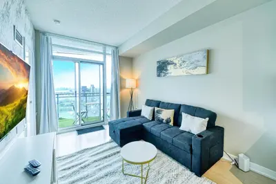 a living room with a couch and a large window at RivetStays - Dan Leckie Suite in Toronto