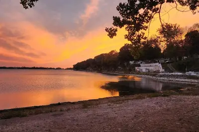 a body of water with a sunset in the background at Sandbanks Beach Cottage in West Lake