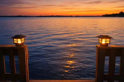 two lights on posts on the water at sunset at Sandbanks Beach Cottage in West Lake