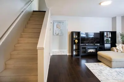 a staircase in a living room with a couch and a television at Spacious & Cozy in the Heart of Town in London