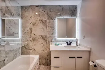 a bathroom with a sink and a tub and a mirror at Modern 2 Bed Unit Near the Falls in Niagara Falls