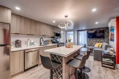 a kitchen and living room with a counter and chairs at Modern 2BR Unit Near the Falls in Niagara Falls