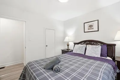 a bedroom with a bed with a blue blanket and two lamps at 5 Bedroom House - 1 Block from the Falls in Niagara Falls
