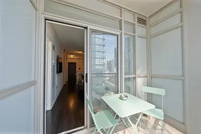 a white table and chairs in a room with a window at Skyline Stays Chic 2BR Steps from Everything in Toronto