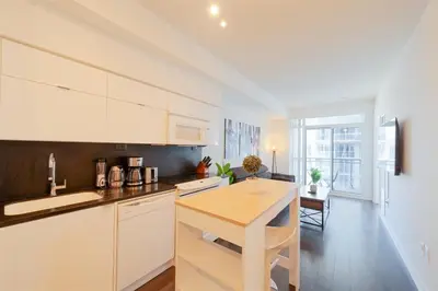 a kitchen with white cabinets and a wooden counter top at Skyline Stays Chic 2BR Steps from Everything in Toronto