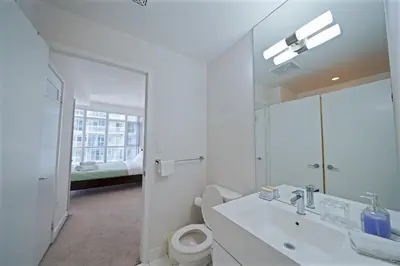 a bathroom with a sink and a toilet and a mirror at Skyline Stays Chic 2BR Steps from Everything in Toronto