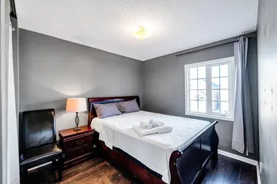 a bedroom with a bed with a chair and a window at Thrilling Homey Escape In Toronto Area in Ajax