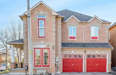 a brick house with two red garage doors at Thrilling Homey Escape In Toronto Area in Ajax