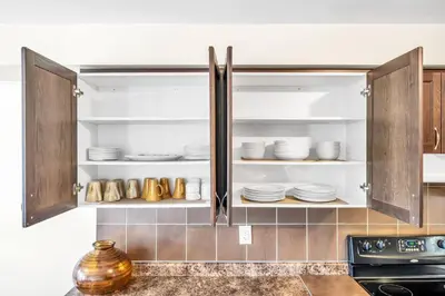 a kitchen with wooden cabinets with dishes in it at Exhilarating Castle Vibes In Toronto Area in Ajax