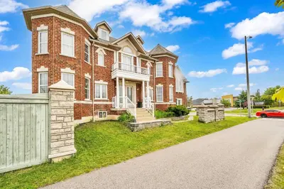 a brick house with a white fence and a driveway at Exhilarating Castle Vibes In Toronto Area in Ajax