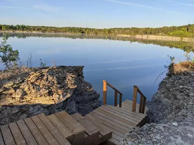 a wooden bridge over a body of water at Woodrush Cabin a Charming Lakefront Tiny Cabin in Victoria Road