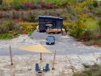 a tiny house in a parking lot with a car at Woodrush Cabin a Charming Lakefront Tiny Cabin in Victoria Road