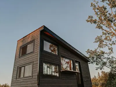 a house with windows on the side of it at Woodrush Cabin a Charming Lakefront Tiny Cabin in Victoria Road