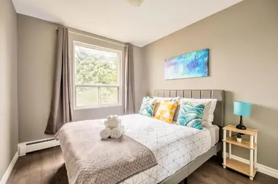 a bedroom with a bed with a teddy bear sitting on a bench at Charming Newly Renovated Condo - Glenview West in Hamilton