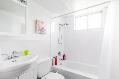 a white bathroom with a toilet and a sink at Charming Newly Renovated Condo - Glenview West in Hamilton