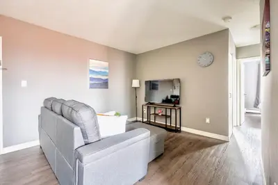 a living room with a couch and a clock on the wall at Charming Newly Renovated Condo - Glenview West in Hamilton