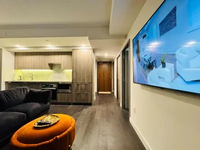 a living room with a couch and a large tv on a wall at Luxury 76 floor 2B2B Downtown Toronto Skyline View in Toronto