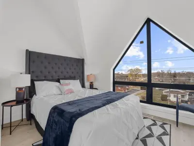 a bedroom with a bed and a large window at 2BR Penthouse Rooftop, Parking, Close to the Falls in Niagara Falls