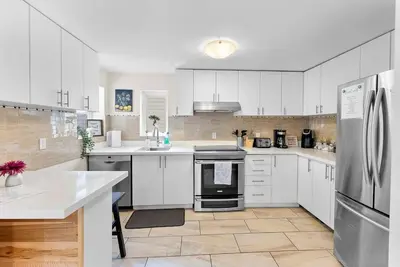 a large white kitchen with white cabinets and appliances at Cozy Family Retreat Minutes From the Falls and Pet Friendly in Niagara Falls