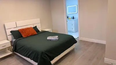 a bedroom with a large bed with an orange pillow at Newly Renovated and Spacious 3BR Private Apartment with 3 Baths & Parking in Richmond Hill
