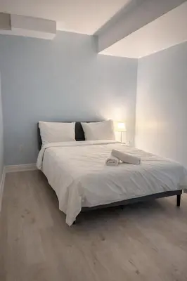 a bedroom with a large bed with white sheets at Modern 2BR Basement Suite Private Entrance in Brampton