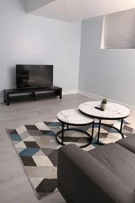 a living room with two tables and a flat screen tv at Modern 2BR Basement Suite Private Entrance in Brampton