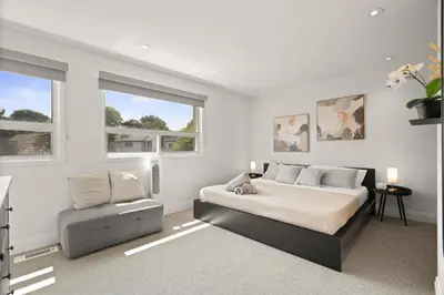 a bedroom with a bed and a chair and windows at 4BR Family Home - Dog-Friendly, Huge Yard, 5 Beds in Pickering