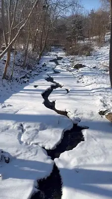 a snow covered river with snow on the ground at Licensed-8 Acre Estate, Trail & Stream with 3 Beds in Hamilton