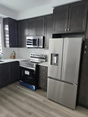 a kitchen with black cabinets and a stainless steel refrigerator at Modern 3BR FriendlyTown Home in Paris
