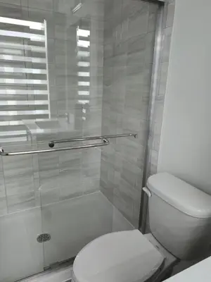 a bathroom with a toilet and a glass shower at Modern 3BR FriendlyTown Home in Paris