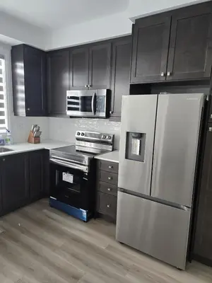 a kitchen with black cabinets and a stainless steel refrigerator at Modern 3BR FriendlyTown Home in Paris