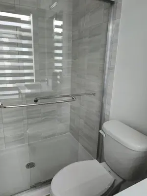 a bathroom with a toilet and a glass shower at Modern 3BR FriendlyTown Home in Paris