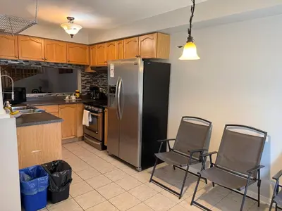 a kitchen with a stainless steel refrigerator and chairs at Spacious Three Bedroom House Wifi Parking in Milton