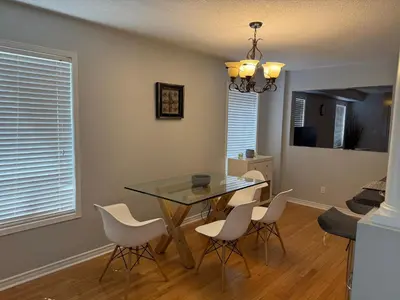 a dining room with a glass table and white chairs at Spacious Three Bedroom House Wifi Parking in Milton
