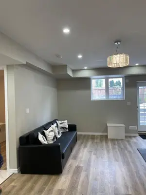 a living room with a black couch and a chandelier at One bedroom and studio Basement Apartment unit sleeps 4 in Oakville