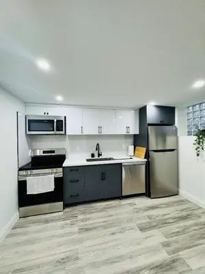 a kitchen with white cabinets and stainless steel appliances at The Urban Executive Suite - Premier Kitchener Loft in Kitchener