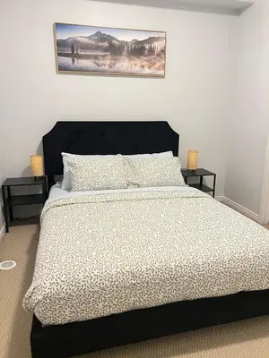a bedroom with a large bed with a black headboard at Peaceful serene oasis with free parking and wifi in Brampton